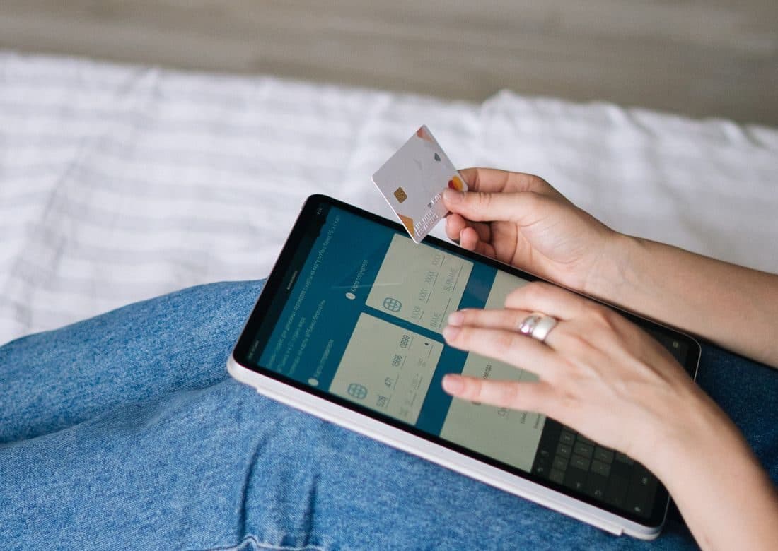 Investor holding a bank card while using a tablet